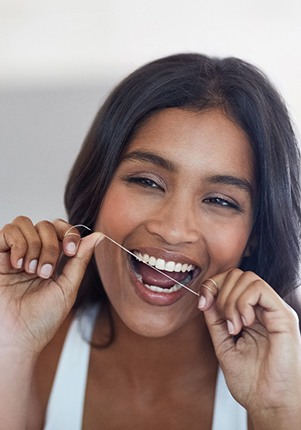 Woman smiling while flossing her teeth