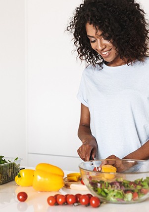 Woman smiling while preparing healthy meal at home