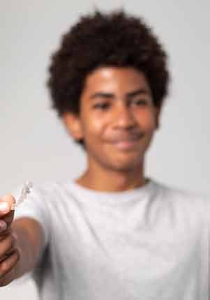 Teen smiling while holding clear aligner