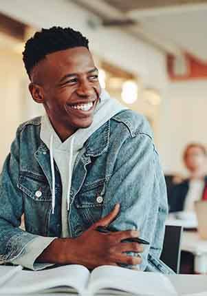 Teen boy smiling at desk in classroom