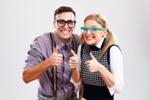 Two people with orthodontics look stereotypically "nerdy" making thumbs-up